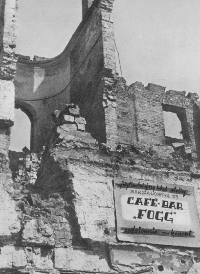 Czarno-białe zdjęcie przedstawiające ruiny budynku. Na ruinach jest tabliczka z napisem: Cafe Bar Fogg.