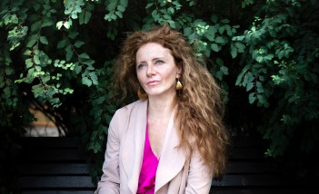 Kobieta z rozpuszczonymi włosami pozuje na tle roślinności.