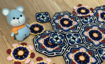 Po lewej stronie stoi niebieska zabawka - miś, obok niej leżą kolorowe serwetki.