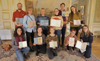 Grupa kilkunastu osób pozuje do zdjęcia, trzymając przed sobą książki.