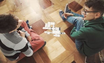 Dwóch młodych chłopców siedzi na podłodze i rozmawia.